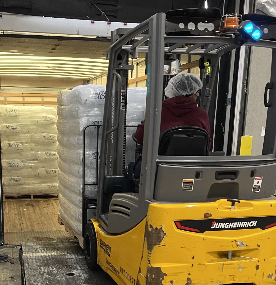 Forklift loading pallets of bagged ice